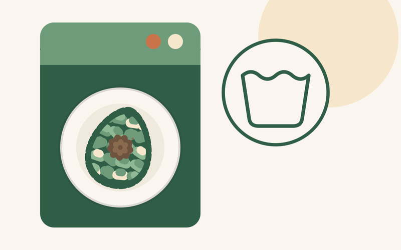 An avocado-shaped snuffle mat inside a washing machine drum beside a machine-wash symbol